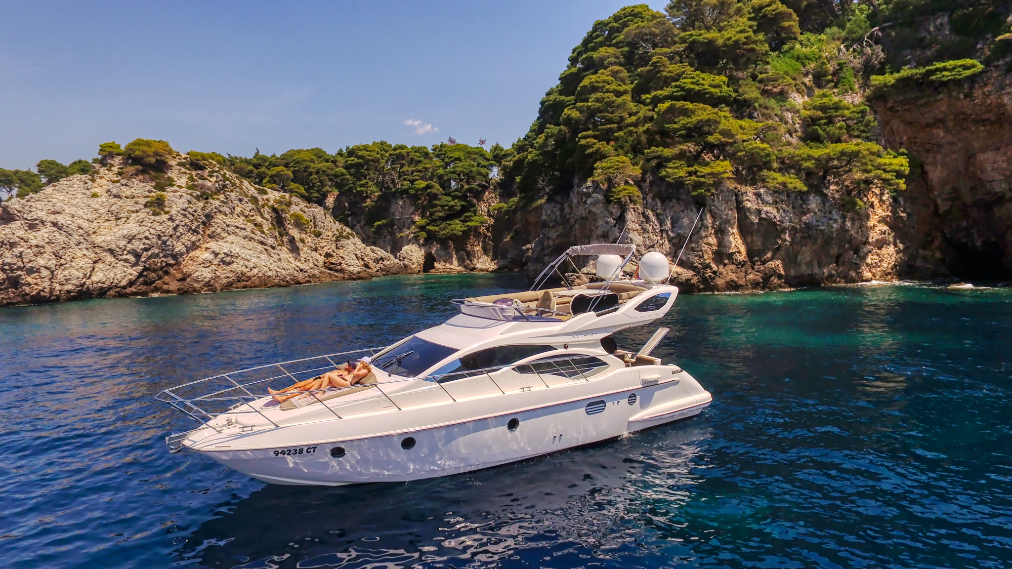 A Dubrovnik Boat Adventure motor yacht anchored in a turquoise cove beneath pine-clad cliffs